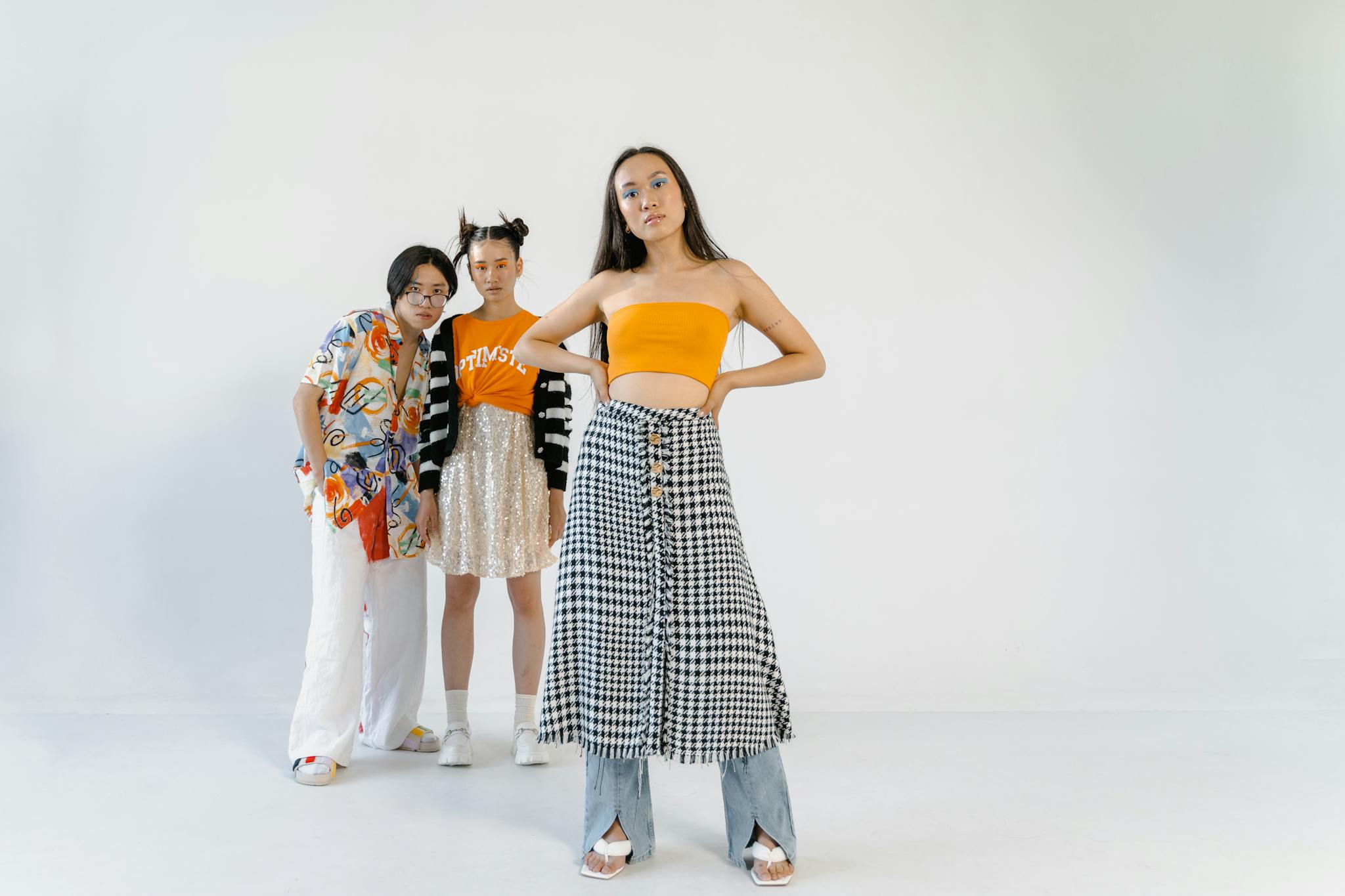 A stylish trio of teenagers posing in fashionable attire during a studio photoshoot.
